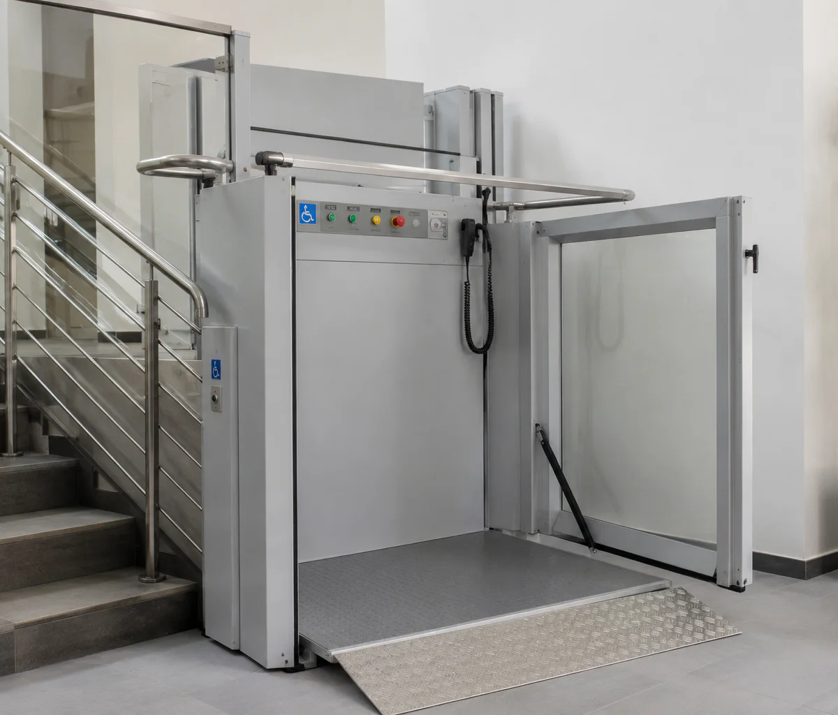 Verticale platformlift naast een trap in een modern gebouw