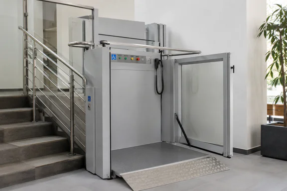 Verticale platformlift naast een trap in een modern gebouw